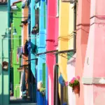 Calle stretta tra case dipinte di rosa, verde e blu a Burano, laguna di Venezia