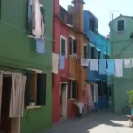 Case dai colori vivaci con il bucato steso a Burano, laguna di Venezia
