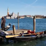 Gondolieri a uno stazio sul Bacino di San Marco con San Giorgio Maggiore sullo sfondo, Venezia