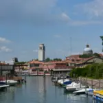 Canale con barche ormeggiate a Castello, il campanile bianco e la cupola di San Pietro sullo sfondo